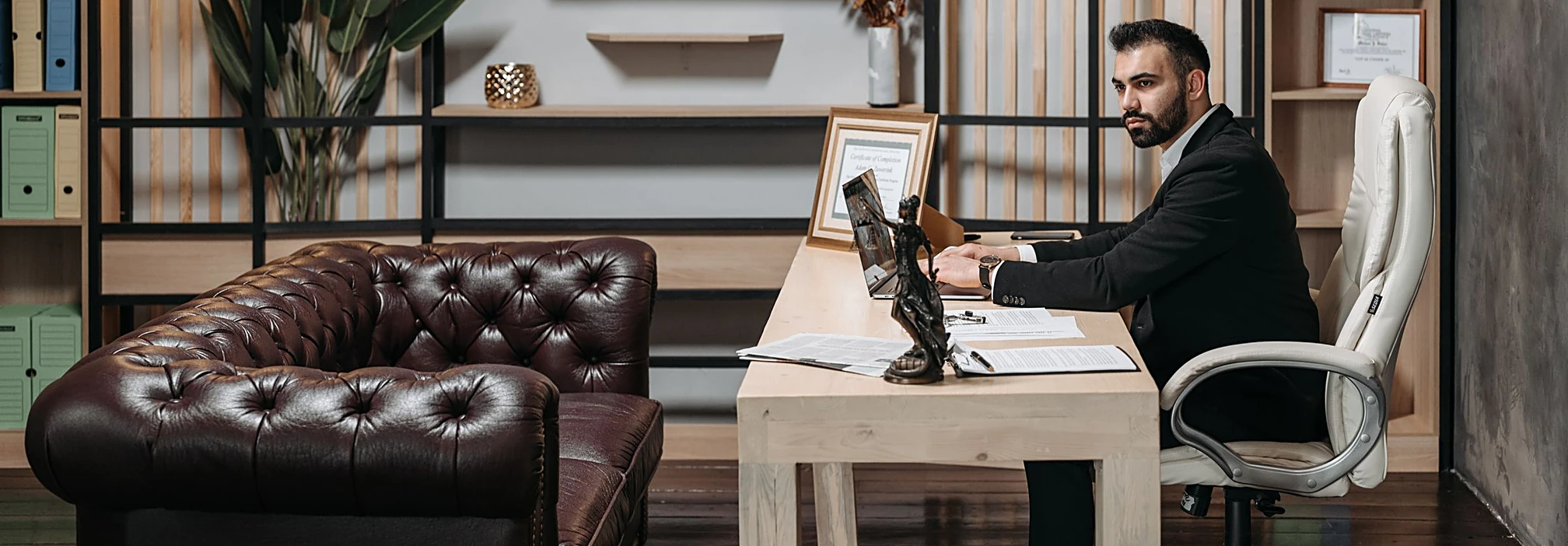An elegant private office with a principal at his desk and a leather chesterfield sofa