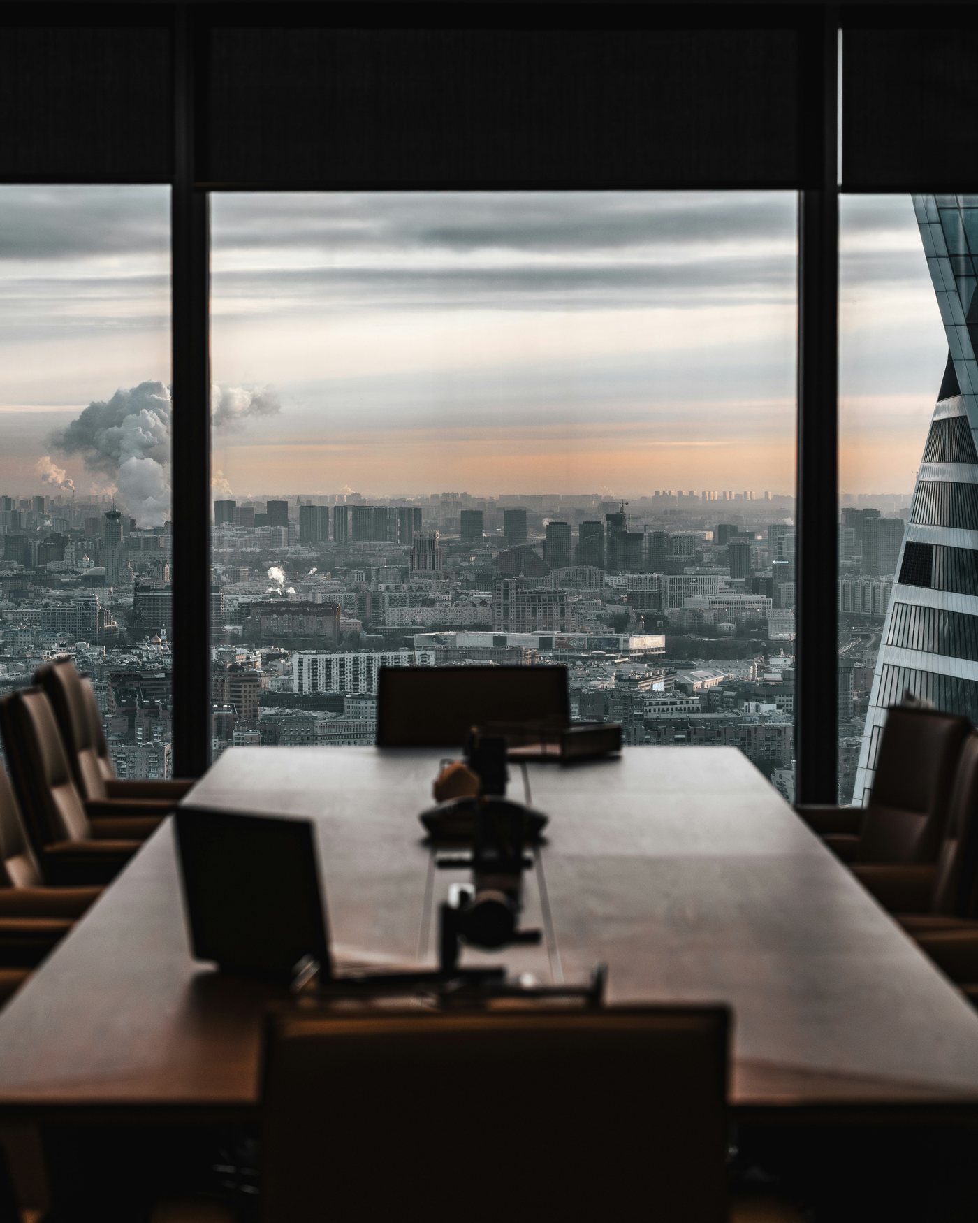An empty, discreet conference room with tall windows over the city